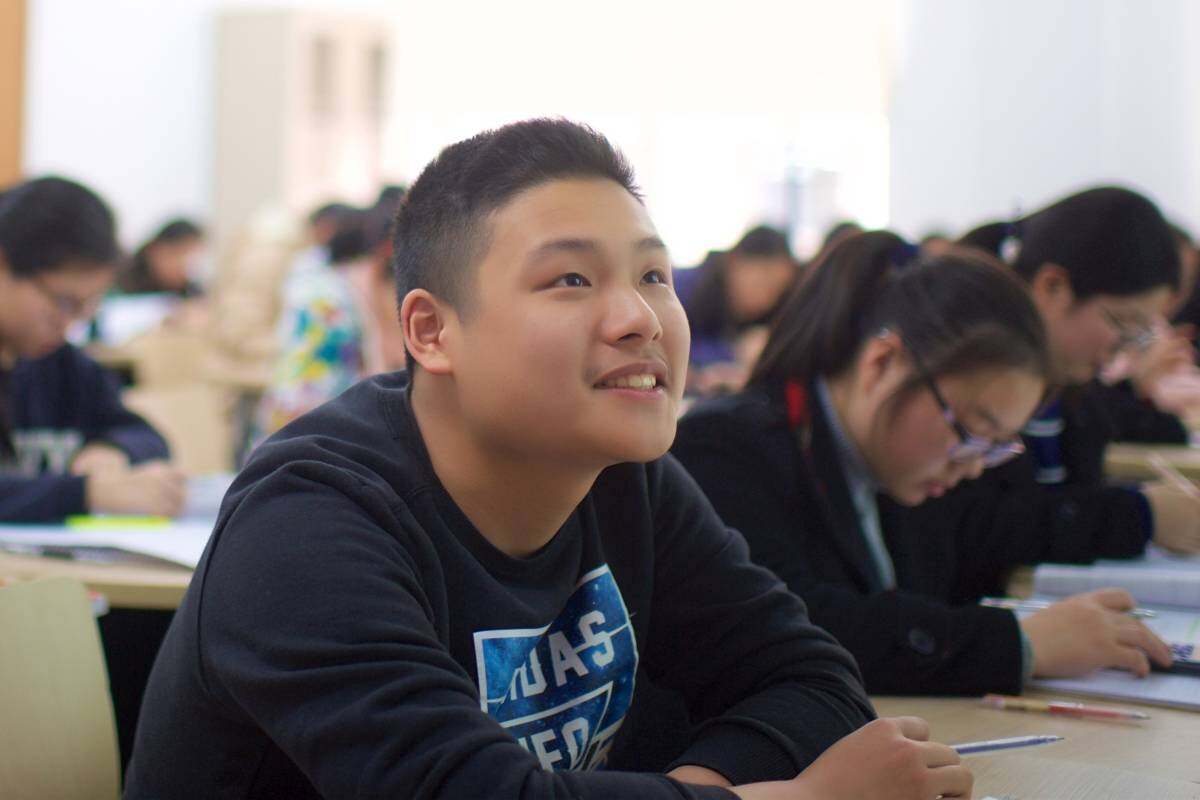 A young person in a classroom looks up to his teacher