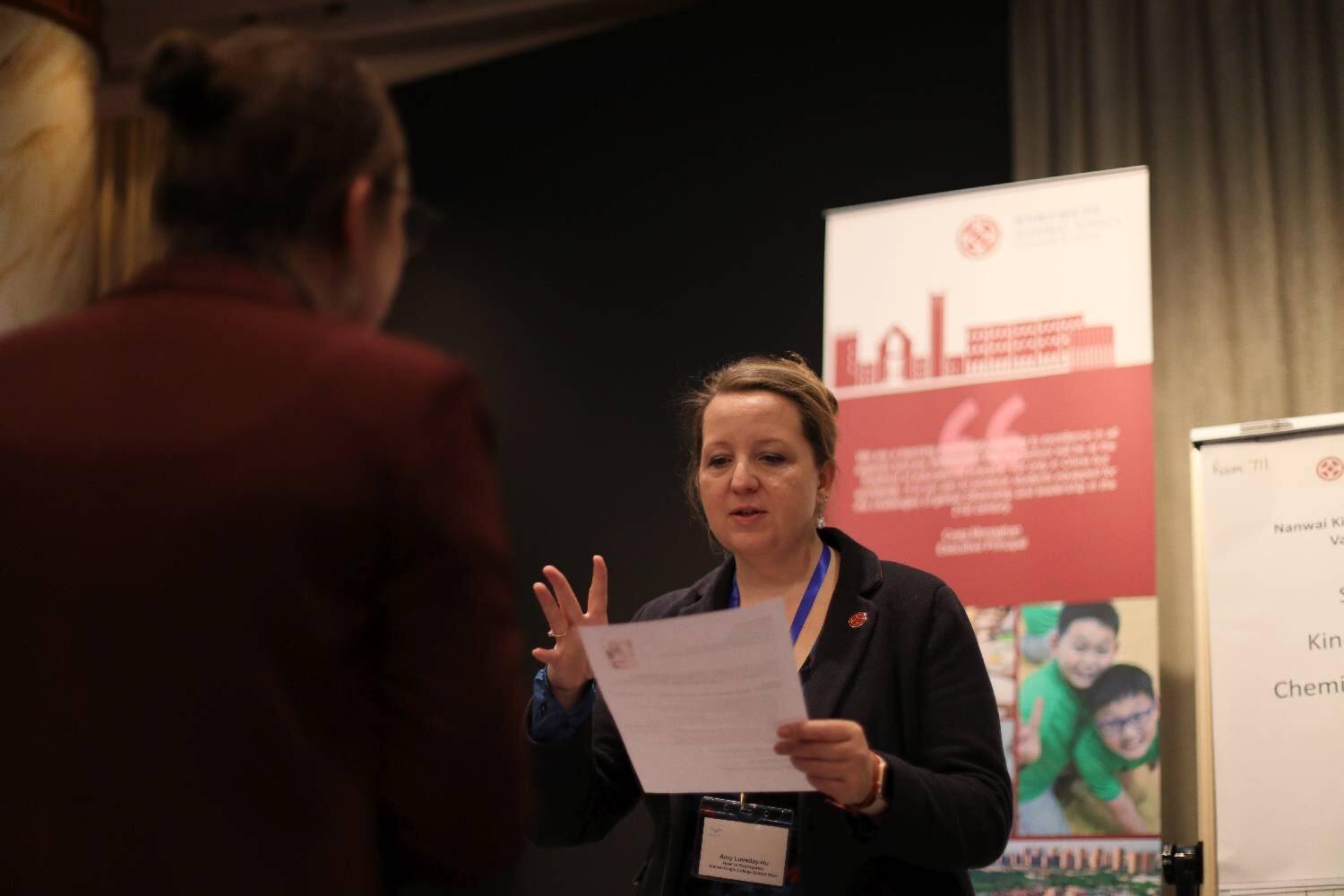 A women looks at a piece of paper at a teacher recruitment fair