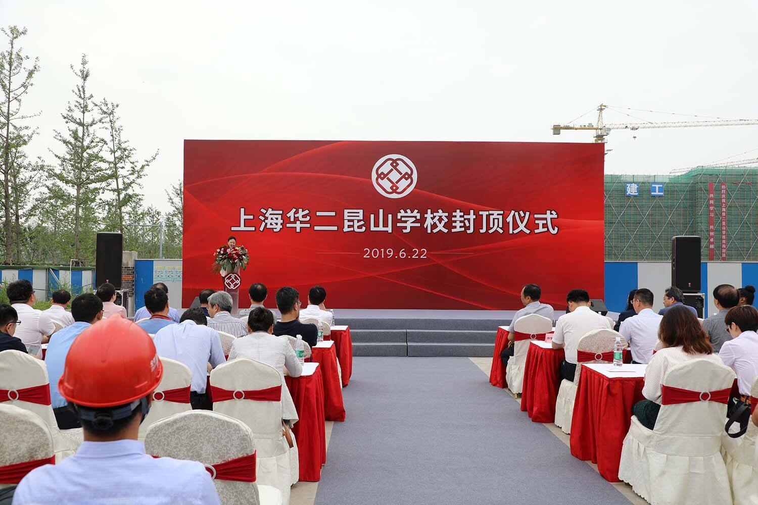 People sit in rows of chairs listening to a speaker at a podium