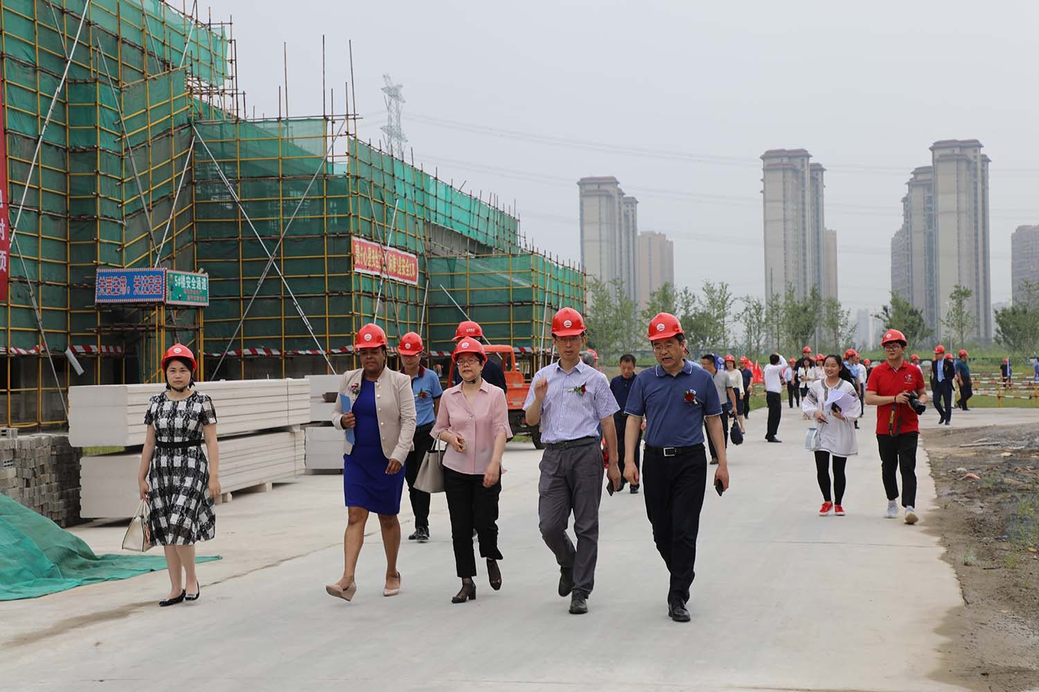 People walk around the construction site wearing hard hats